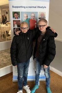 2 brothers affected by ED at the Christmas Party, stood in front of a banner showing the ED guide book