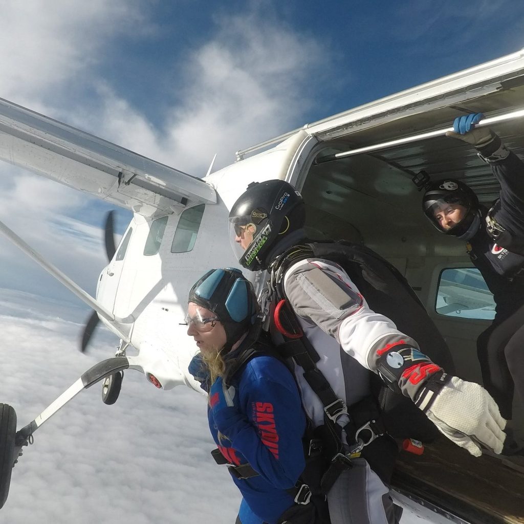 member of the ed society jumping out of a plane strapped to an instructor for a sky jump