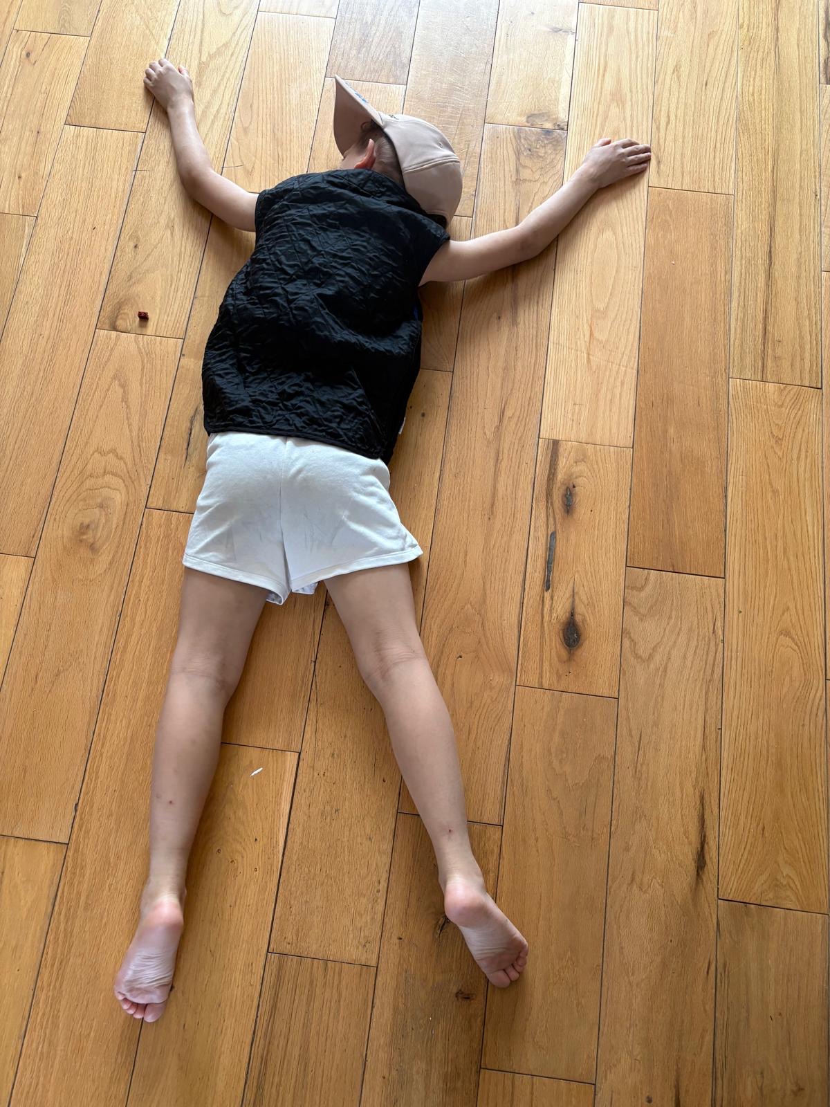 image of Amar laying face down spread eagle on wooden floor cooling down